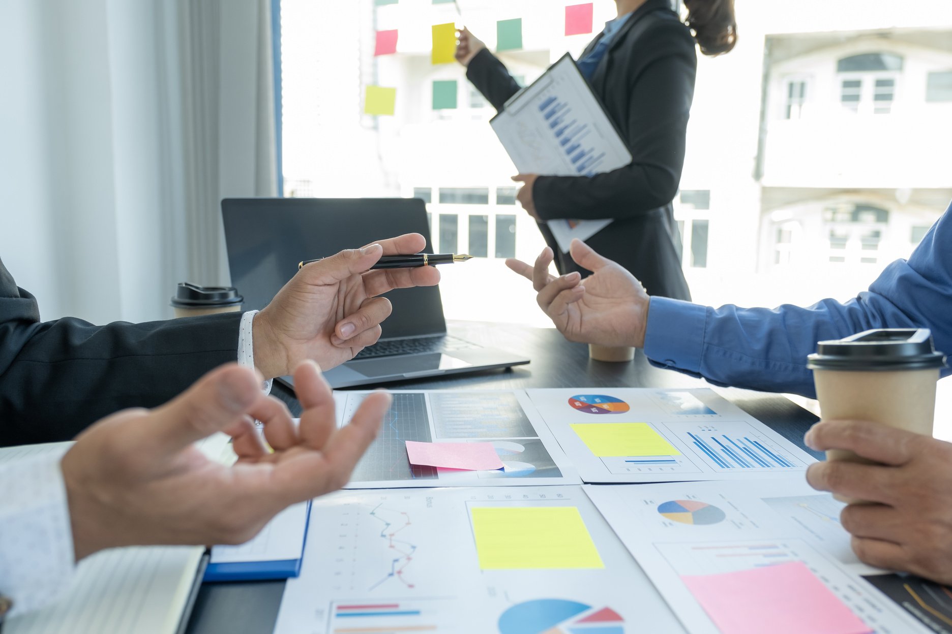 hand holding pen, businesswomen and businessmen team meeting to plan strategies to increase business income. Have a brainstorming finance graph analysis and discussing for the new target success